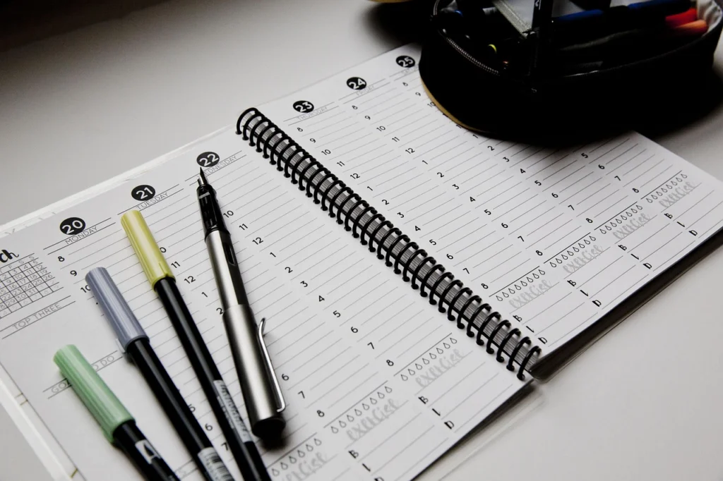 Woman reviewing her weekly planner with a pen, practicing planning hacks for consistency