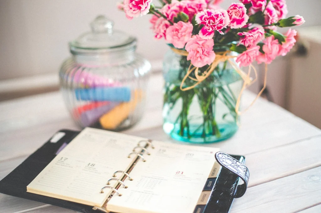 A woman writing in her planner at a desk, planning her week for work-life balance