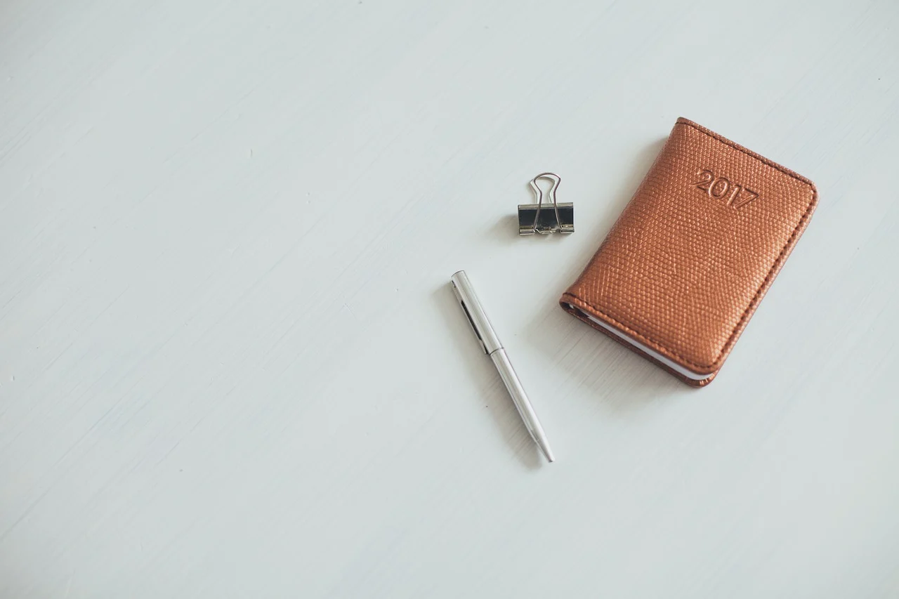 A simple planner notebook open on a desk, showing weekly schedule with work and personal time blocks